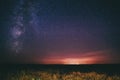 Night Starry Sky Above Field And Yellow City Lights On Background. Night View Of Natural Glowing Stars Royalty Free Stock Photo