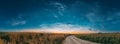 Night Starry Sky With Glowing Stars Above Countryside Landscape. Noctilucent Clouds Above Rural Field With Young Rye And Royalty Free Stock Photo