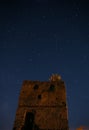 Night starry sky over an abandoned stone tower. A falling star is visible. A deep dark night. Royalty Free Stock Photo