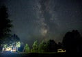 Night starry sky scene with illuminated cottage