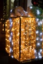 Night street Christmas decoration of gift shape with festive lamps illumination, vertical photography, soft focus on synthetic