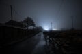 Night street country road with buildings and fences covered in fog lamp . Or Mysterious night in Azerbaijan mountain village Royalty Free Stock Photo