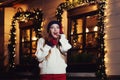 Night street portrait of young beautiful woman acting thrilled, wearing stylish knitted clothes. Model expressing joy Royalty Free Stock Photo