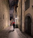 Night Street Rain weather women walk with red umbrella on Medieval Old town of Tallinn night blurred light and Christmas decoratio Royalty Free Stock Photo