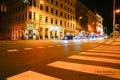 Night street scene from street level view people, cars, pedestrian crossing in night lights from street and surrounding shops and