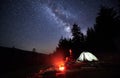 Night camping in mountains near forest with campfire and tourist tent. Royalty Free Stock Photo