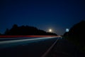 a night track with a moon and blurred lights from the headlights of cars.long exposure time. Royalty Free Stock Photo