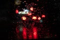 Night traffic lights of big city, rain drops on car windshield glass, focus on raindrops. Rain background of a night blurred city Royalty Free Stock Photo