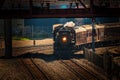 Night train passing under a bridge on tracks Royalty Free Stock Photo