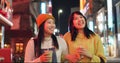 Night, travel and Japanese women in a city walking, talking and bonding with milkshake drink outdoor. Happy, female and