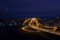 Night city landscape with illuminated road junction, industrial and residential buildings