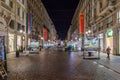 Night View of Beautiful Illuminated Via Dante Street in Milan, Italy. Stores and National Flags all across the Street