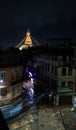 Night view of the brightly lit Boudha stupa, from the building in one of the city streets, in the rain