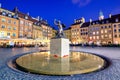 Night view of the bronze statue of Mermaid on the Old Town Market Square of Warsaw, surrounded by colorful old houses.