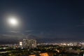 Night view of the central district of the city of Almaty with the moon in the sky