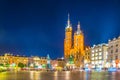 Night view of the church of Saint Mary with statue of adam mickiewicz on the rynek glowny main square in the polish city