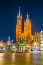 Night view of the church of Saint Mary with statue of adam mickiewicz on the rynek glowny main square in the polish city