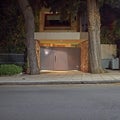 Night view of an elegant contemporary house entrance grey door and huge tree trunks Royalty Free Stock Photo