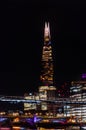 Night view of the fully illuminated London skyscraper The Shard, office buildings and two bridges and a ferry over the River Royalty Free Stock Photo