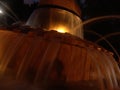 Night view of the Herzel local`s park frog fountain flowing water, illuminated by warm yellow lights