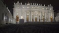 Night view of illuminated Saint Peter's Basilica facade, chairs for parishioners