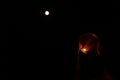 Night view of karwa Chauth pooja with a glowing diya against the moon