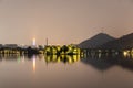 Night view of the lake and the city. Trees with light on the lake, High luminous skyscrapers, mountains. Reflection in the lake.