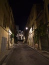 Night view of narrow alley in Arles, Provence, France with old traditional buildings, street lights and Roman amphitheatre. Royalty Free Stock Photo