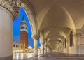 Night view of Piazza San Marco with Doge`s Palace Palazzo Ducale columns and Campanile of Basilica in arch. Venice, Italy.