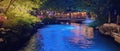 NIGHT VIEW OF RIVER WITH WOODEN BRIDGE, PARK, AND RESTAURANT Royalty Free Stock Photo