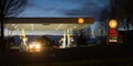 Night view of Shell gas station forecourt with beams of car headlight
