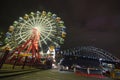 Night view of Sydney Luna Park ferris wheel with Harbour Bridge and Opera House on the right