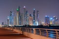 Night view to Dubai iconic skuscrappers panorama. Amazing illumination of the buildings reflected in the Gulf