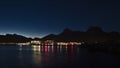 Night view of village SvolvÃÂ¦r, Lofoten, Norway with illuminated buildings reflected in the calm water, wooden stockfish racks.