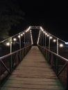 Night View of Wooden Suspension Bridge Decorated with String Lights Royalty Free Stock Photo