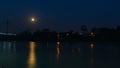 Night view with yellow moon of the bridge over the Aguarico river next to the city of Lago Agrio with lights of houses lit among Royalty Free Stock Photo