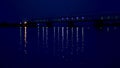 night, in the water the bridge and its lights are reflected. A long bridge over the river. Royalty Free Stock Photo
