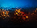 Night window with raindrops and street light of lanterns. Wet glass with multi-colored shiny drops. Blurred photo Royalty Free Stock Photo