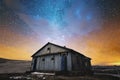 Night winter landscape. Abandoned wooden house in the background of the night starry sky in bright colors and sunset Royalty Free Stock Photo
