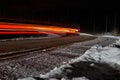 Night winter road in the forest. Cars drive along the road and leave headlights on. Spectacular streak of light Royalty Free Stock Photo