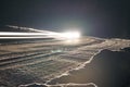 Night winter road in the forest. Cars drive along the road and leave headlights on. Spectacular streak of light Royalty Free Stock Photo