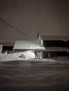 Night winter Russian landscape. Old wooden buildings, a barn or a bathhouse covered with snowdrifts. Royalty Free Stock Photo