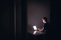 Night work with laptop in dark home office room. Young man using notebook computer. Coder, programmer, hacker, freelance. Royalty Free Stock Photo