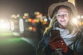 Night. Young woman is standing on city street and is looking at screen of smartphone. Girl uses digital gadget, chatting Royalty Free Stock Photo