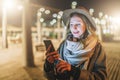 Night. Young woman is standing on city street and is looking at screen of smartphone. Girl uses digital gadget, chatting Royalty Free Stock Photo