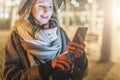 Night. Young woman is standing on city street and is looking at screen of smartphone. Girl uses digital gadget, chatting Royalty Free Stock Photo