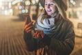 Night. Young woman is standing on city street and is looking at screen of smartphone. Girl uses digital gadget, chatting Royalty Free Stock Photo