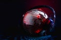 Nightclub music and nightlife concept with a disco ball cover in mirror wearing headphones reflecting the red and blue light in a