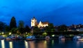 Nightime view of the illuminated Notre Dame catholic church in Dole with houseboats on the Doubs River in the foreground