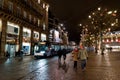 Nightime view of people visiting the Place Kleber Square in Strasbourg during the famous Christmas market with a tram approaching